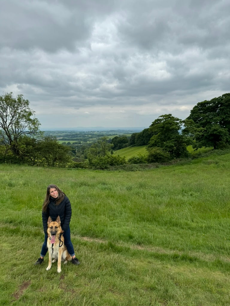 Petite woman with her German Shepherd, Albus, in a scenic landscape, capturing natural beauty and timeless style.