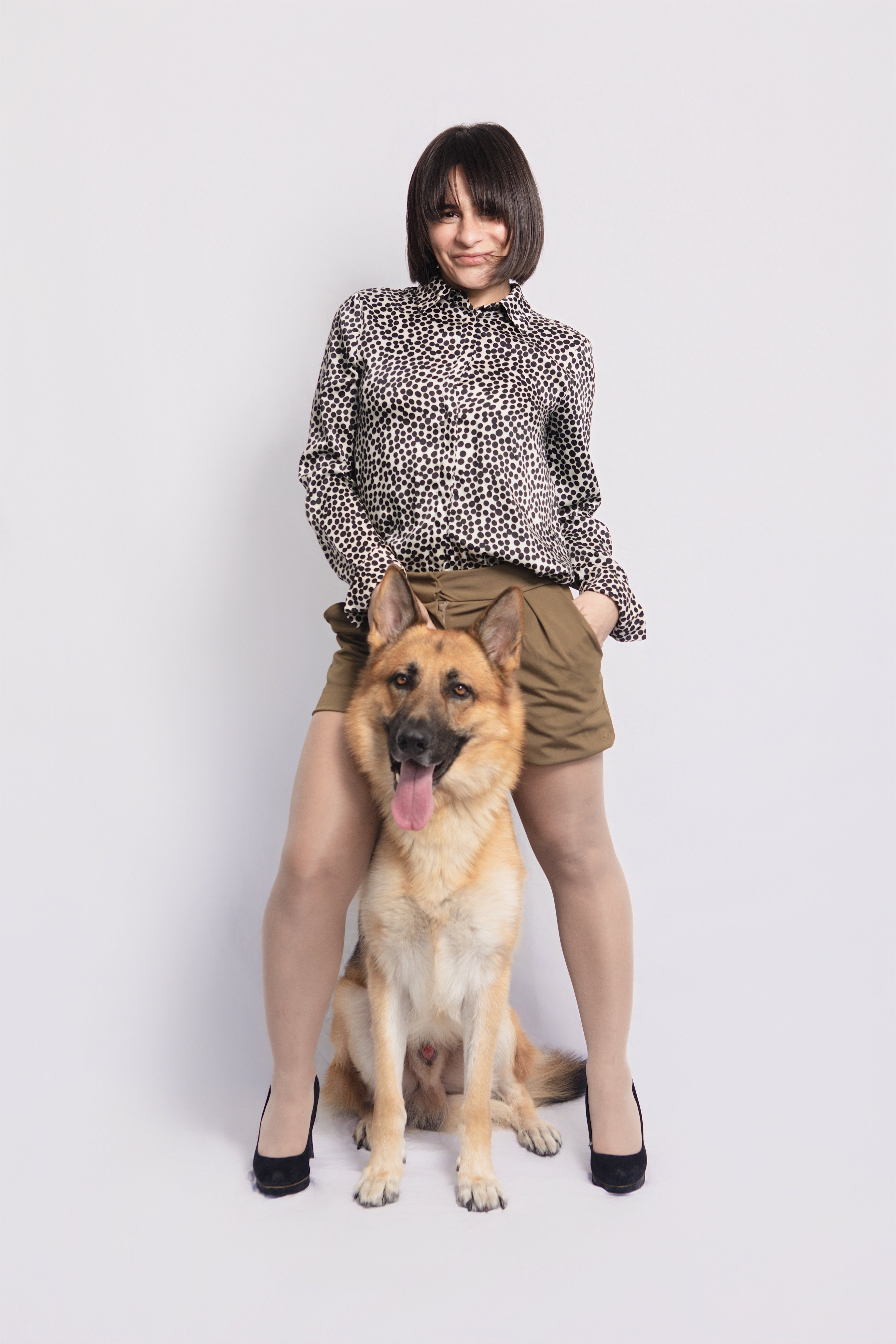 Woman wearing Mariana Tailored Petite Shorts in olive green, designed for petite women 5'3" and under, standing with a German Shepherd dog.