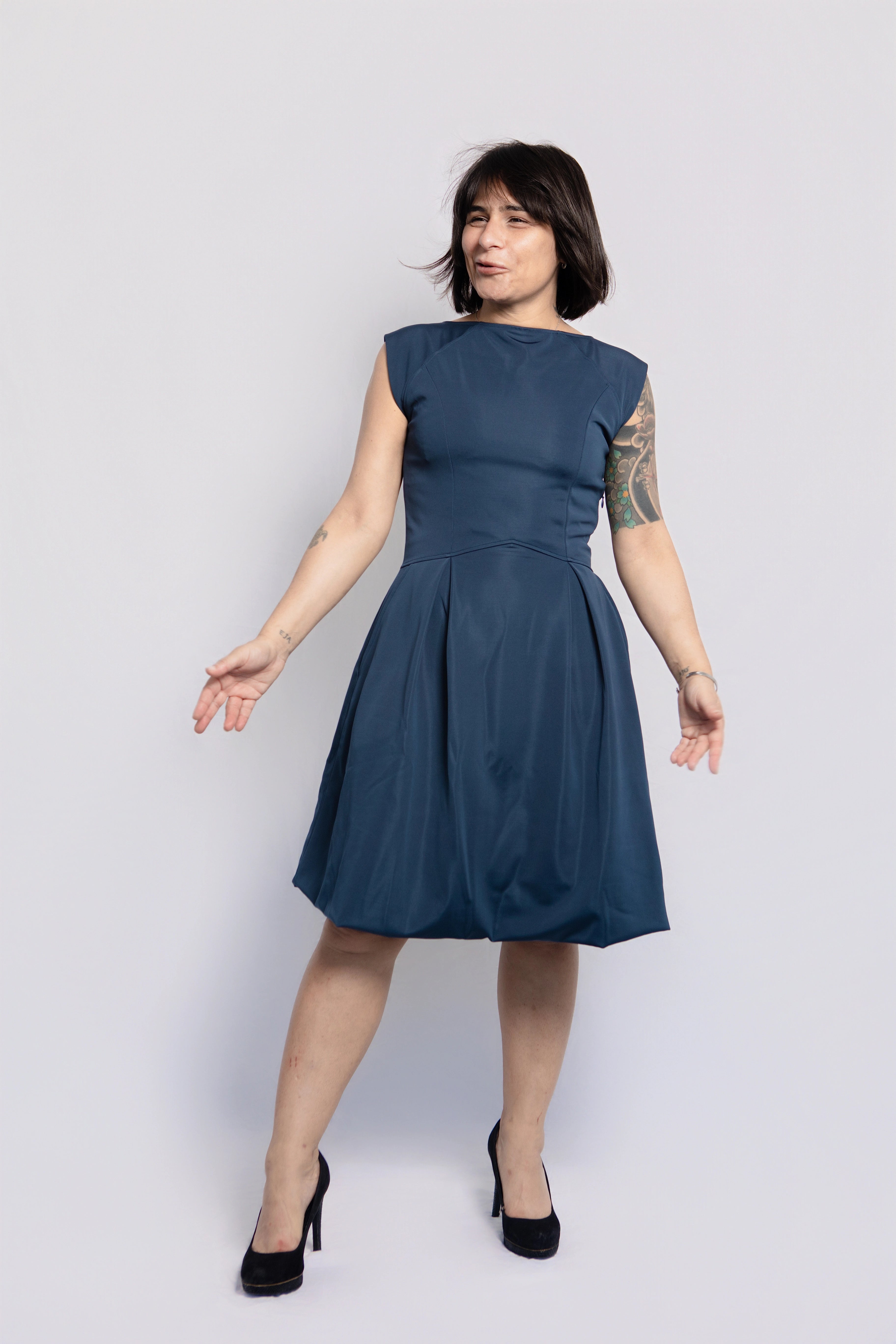 Petite woman wearing elegant blue midi dress with pockets, designed for women 5'3 and under. Timeless petite-friendly fashion made in Portugal, styled with heels