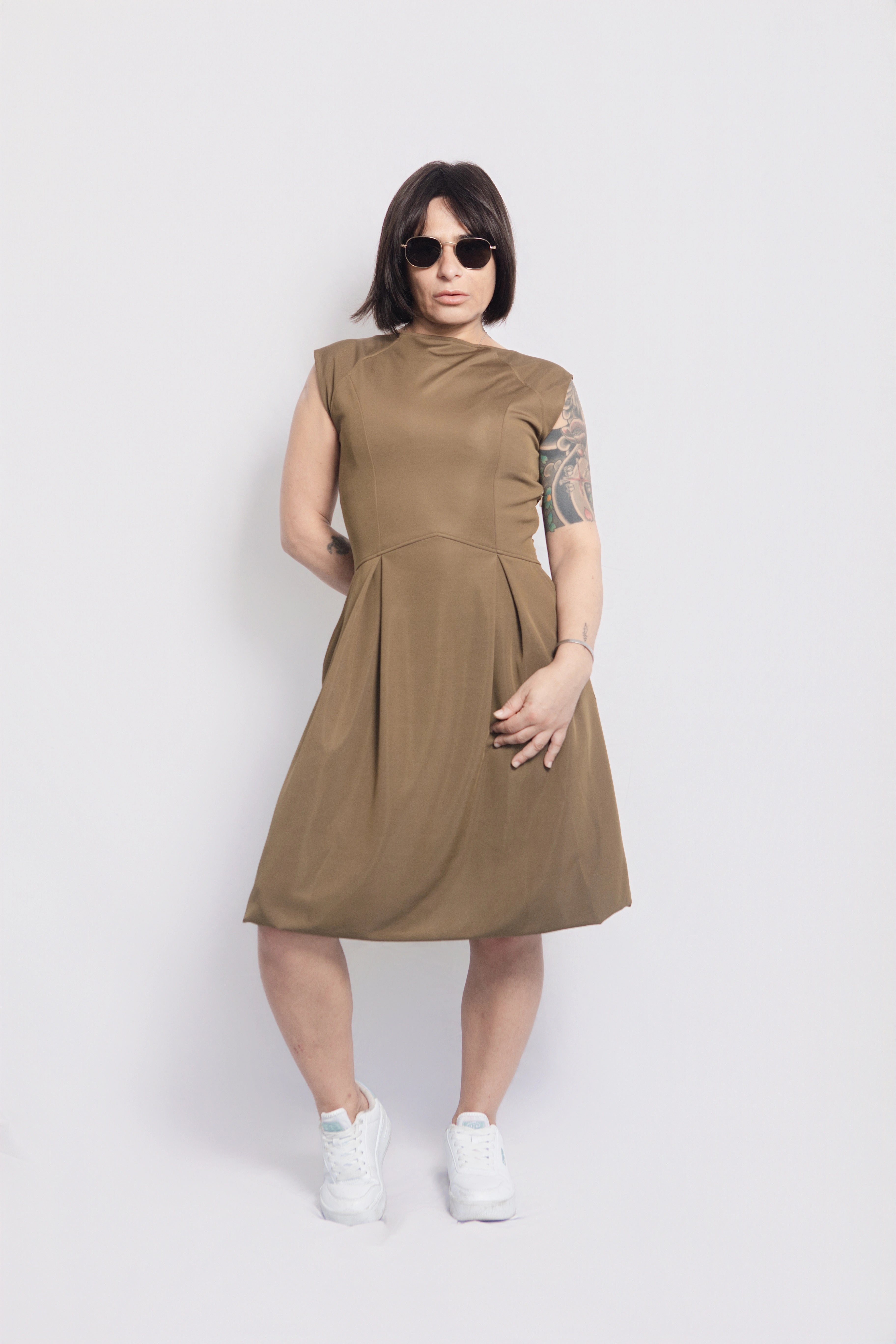 Petite woman wearing olive green midi dress styled with white trainers and sunglasses, versatile petite-friendly fashion made in Portugal, timeless daywear look
