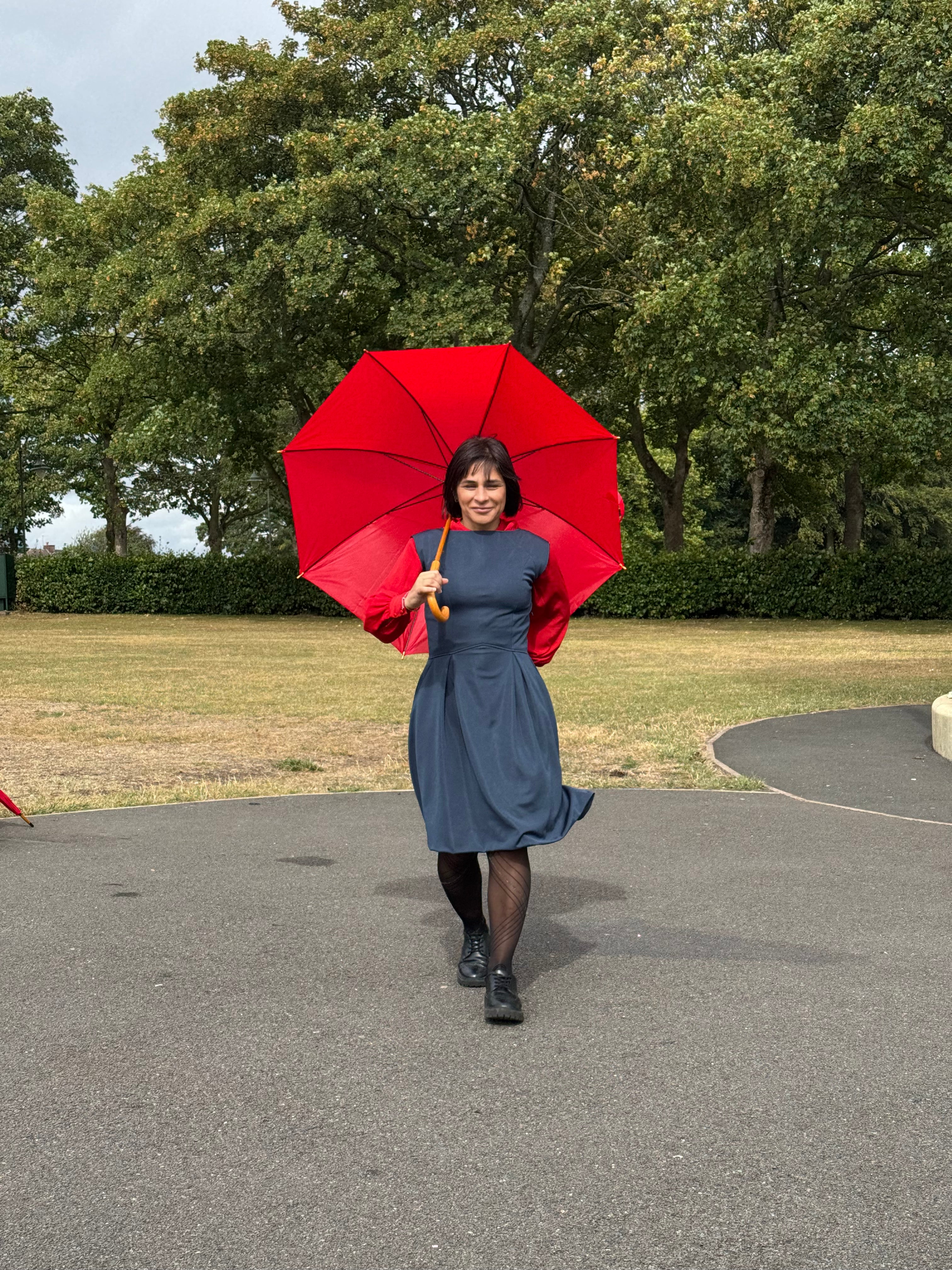 Woman wearing the Eloise Azorean Blue Midi Dress holding a red umbrella, showcasing timeless petite fashion designed for real mature women 5'3" and under.