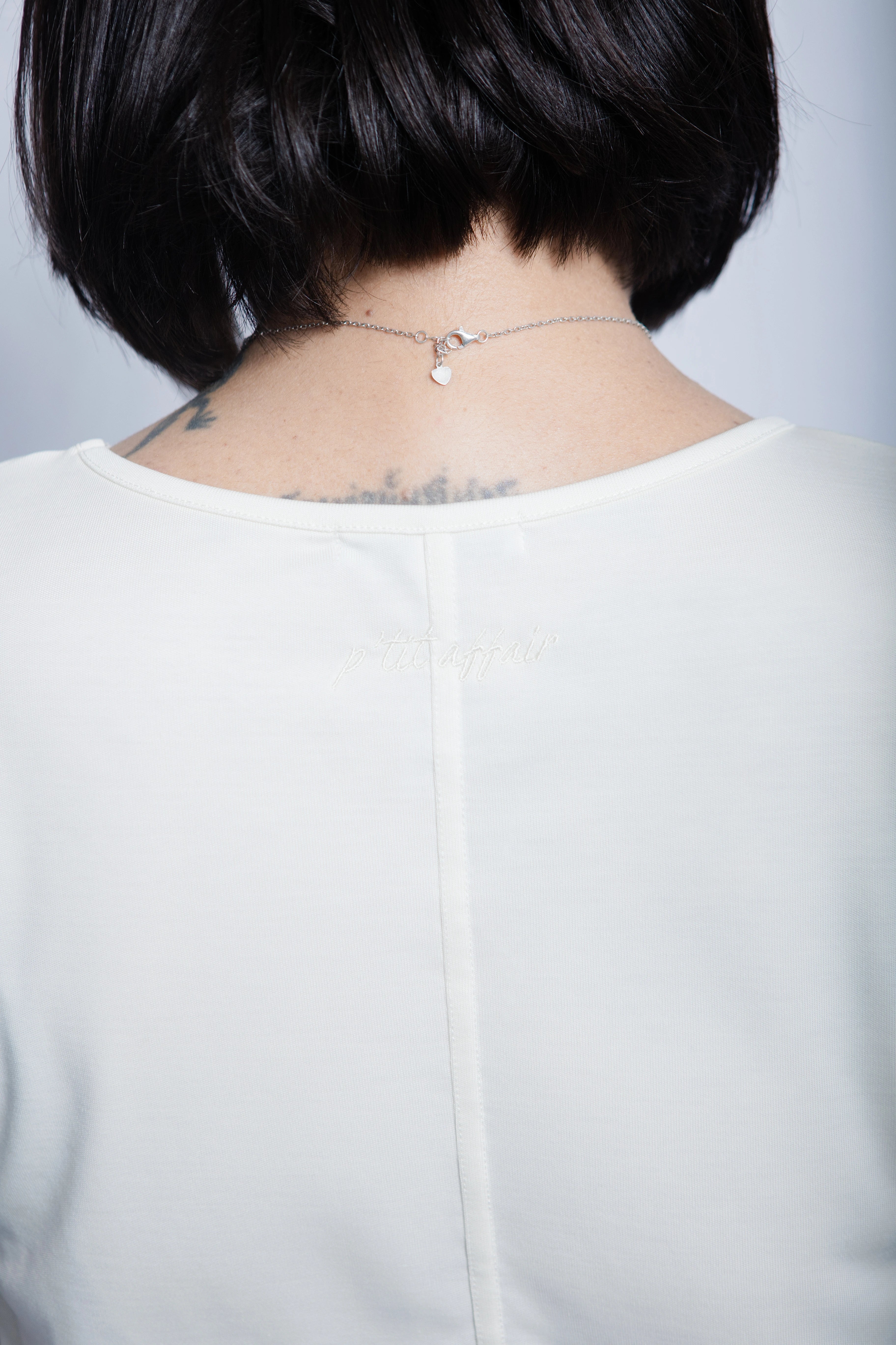 Close-up of premium petite white T-shirt showing embroidered logo detail on the back neckline, timeless luxury fashion made in Portugal
