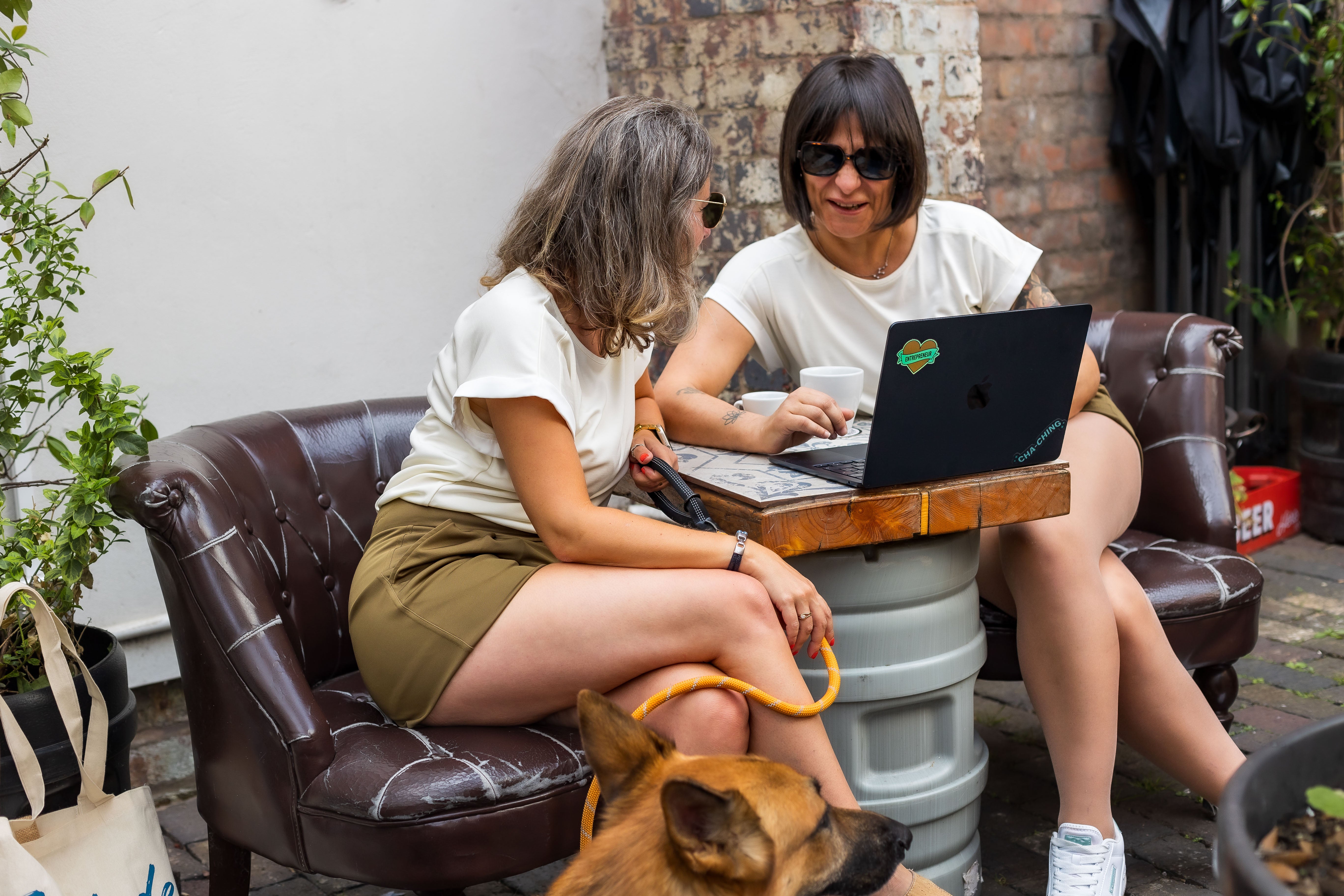 Two petite women wearing P’tit Affair Millie T-shirt and Mariana tailored shorts at a café, styled as a relaxed lifestyle look
